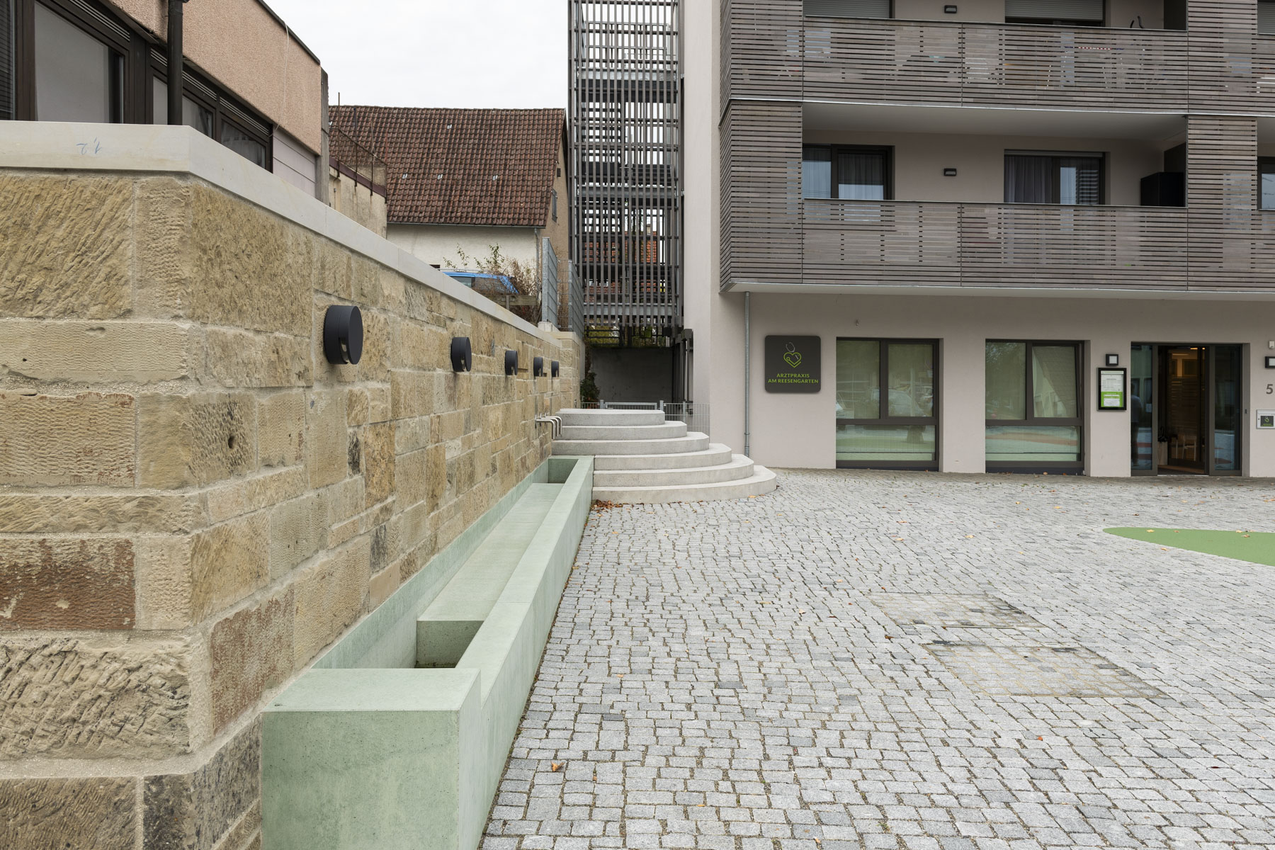 Steinmauer mit vorbereitetem Wasserspiel an öffentlichem Platz mit Treppenaufgang