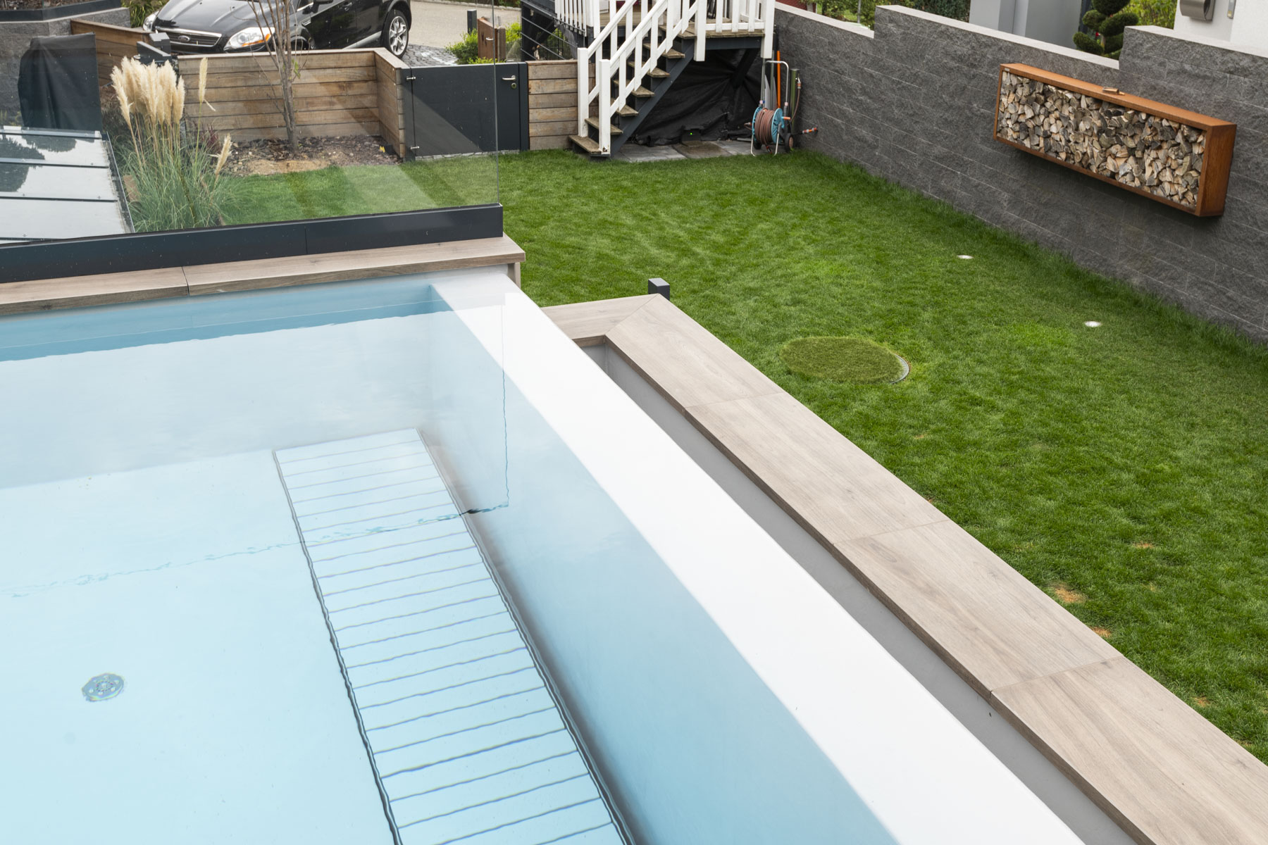 Detailansicht Swimmingpool mit grünem Rasen und kunstvoll gestalteter Steinmauer